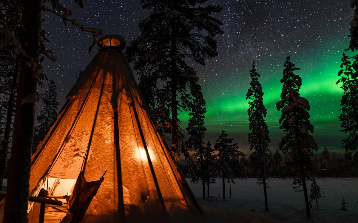 A campfire burning in the snow in a dark clearing outside Levi